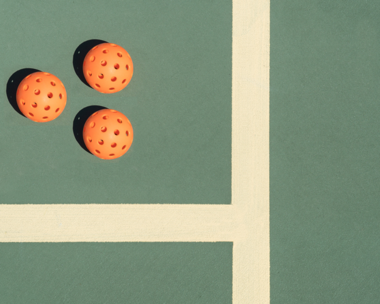 Three orange balls on a tennis court.