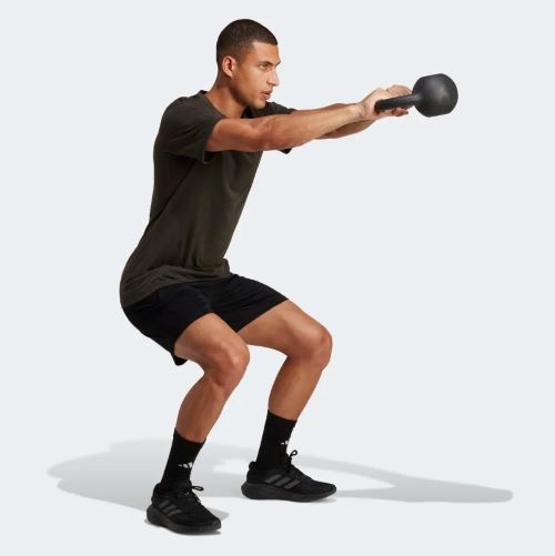A man is squatting with a kettlebell.