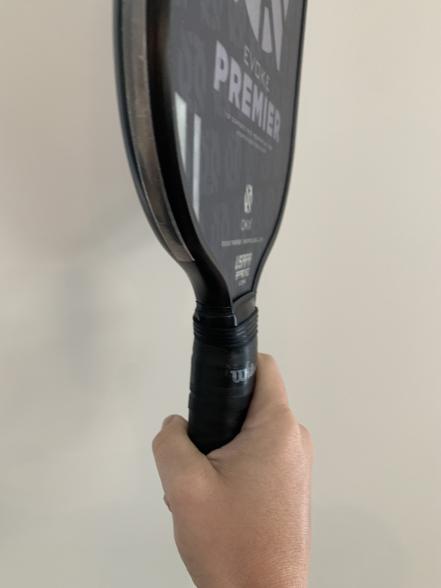 A person holding a tennis racket with the word premier on it.