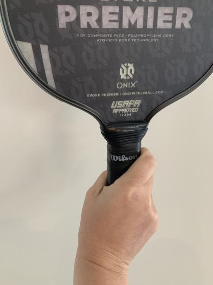 A person holding a badminton racket with the word premier on it.