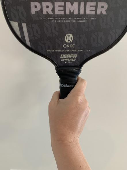 A person holding a tennis racket with the word premier on it.