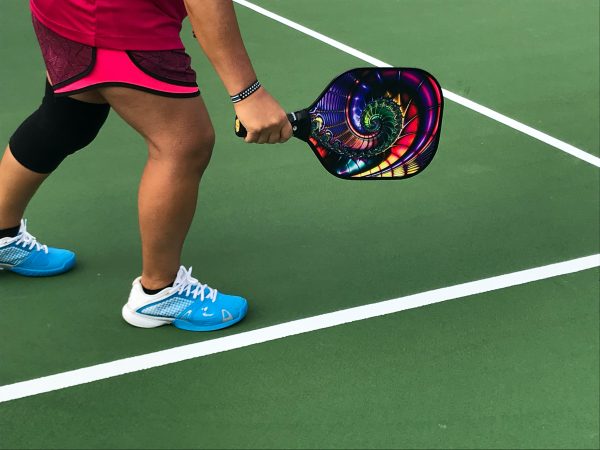 Woman crossing over to hit a pickleball ball with her paddle