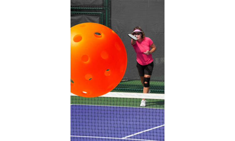 Close-up of a pickleball with a player in the background. 