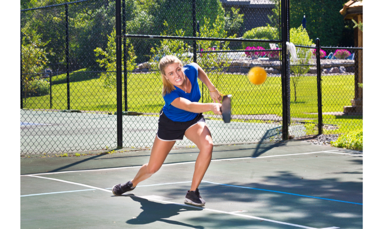 Woman pickleball player hitting a ball on the pickleball court