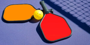 Two paddles and a ball on a tennis court.