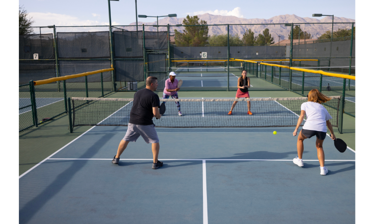 Four pickleball players playing doubles with similar pickleball skill levels. 