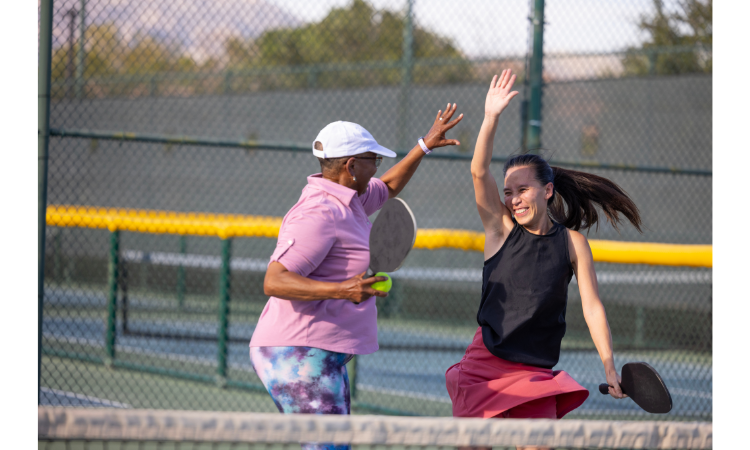 Women's pickleball doubles pairing giving each other a high five. 