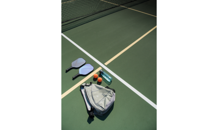 Pickleball paddles, bag, balls, and water bottle for pickleball open play.